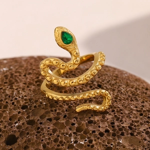 Detail of 18K gold snake ring with green teardrop gemstone on volcanic rock base