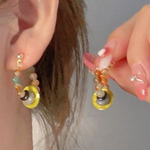 Close-up of elegant butterfly stud earrings with colorful beads and zircon stones