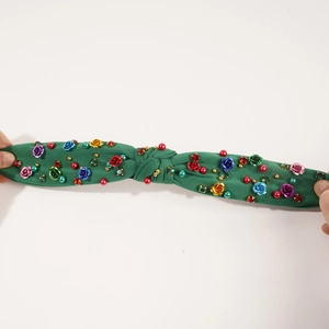 Close-up of green fabric headband with handcrafted roses and colorful bead embroidery