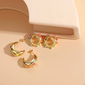 Detail of bohemian gold earrings with colorful enamel dots and thick crescent hoop design