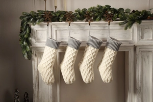 Detail von gestrickten Weihnachtssocken mit Rautenmuster an einem weißen Kamin aufgehängt