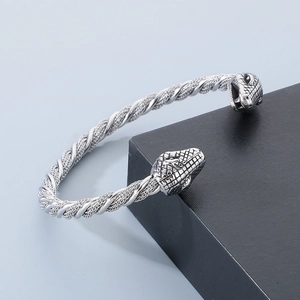 Vue détaillée du bracelet câble torsadé en acier inoxydable argenté avec têtes de serpent