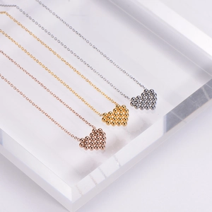 Three beaded heart necklaces in gold, rose gold and silver finishes on acrylic blocks