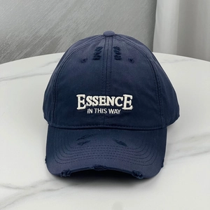 Detailed view of distressed navy baseball cap with white embroidered text on washed cotton