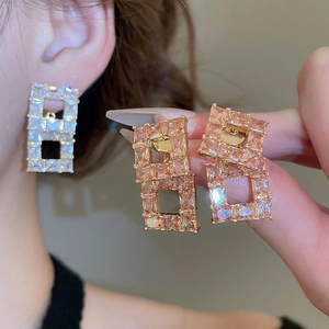 Detailed close-up of 18K gold plated earrings with champagne zircons in geometric design