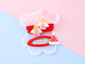 Detail of Christmas hair clips with angel charms and red ribbon on bear-shaped card