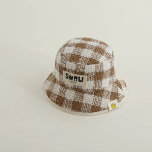 Nahaufnahme von braun-weißem Tweed-Fischerhut mit besticktem Buchstaben-Aufnäher