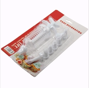 Manual cake decorator set with white plastic syringe and various nozzles in blister packaging