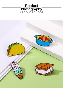 Macro view of cartoon taco, pot, ice cream, and cookie enamel pins on a geometric background