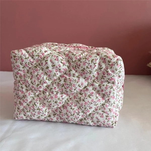 Detail of the quilted texture and pink floral pattern on the cotton makeup bag