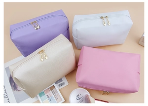Dettaglio di quattro borse da trucco in pelle PU impermeabile in viola, bianco e rosa