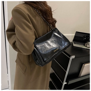 Detail of glossy black leather handbag with chain strap and gold fashion lettering