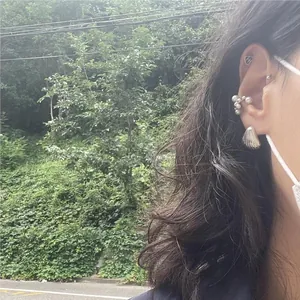 Detail of silver shell earring and pearl ear cuff set on model with street background