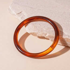 Close-up of vintage amber-toned acrylic bangle with tortoise shell pattern on stone