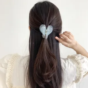 Detail view of heart-shaped blue hair claw clip worn on long brown hair from behind