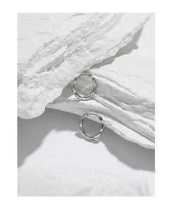 Detail showing the twisted bamboo texture of silver hoop earrings on a white stone
