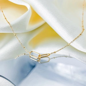 Close-up of golden geometric interlocking oval rings with refined station bead chain