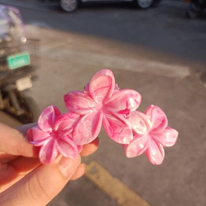 Detailed view of pink flower hair claw clip with marble texture in natural light