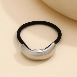 Close-up of sleek silver-tone metal hair cuff with elastic band on elegant beige base