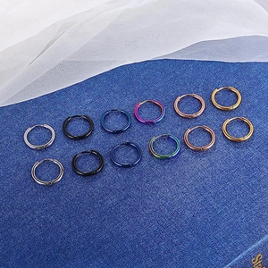 Set of 12 multi-color titanium steel hoop earrings displayed on elegant fabric background