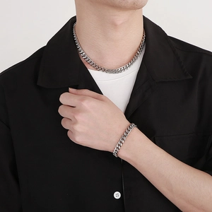 Close-up of a men's polished silver curb chain necklace and bracelet set on a model
