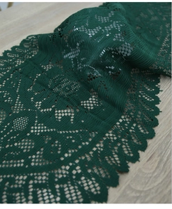 Detailed close-up of dark green lace table runner with hollow-out floral pattern and scalloped edges