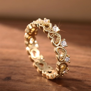 Macro view of gold heart ring featuring openwork design and sparkling white stones