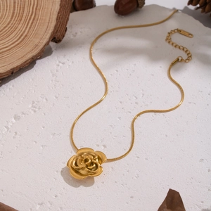Detail of elegant gold rose pendant on a snake chain over a rustic wooden background
