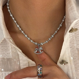 Elegant gold plated horse pearl necklace with sparkling crystals on a white sequin shirt