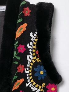 Makroaufnahme der Blumenstickerei und schwarzen Kunstpelzbesatz an dieser Boho-Weste