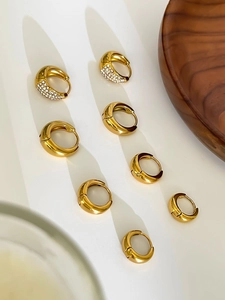 Détail de créoles dorées polies avec zircons transparents au style minimaliste en goutte d'eau