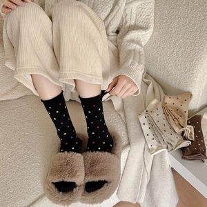 Polka dot wool crew socks for women shown with cozy slippers in a warm home setting