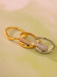 Detail showing stacked geometric V-shaped and rhinestone rings in gold and silver finish