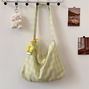 Detail of green gingham canvas tote bag with a yellow flower charm on a white background