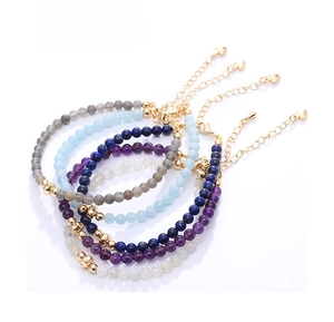Detail of colorful gemstone beaded bracelets with gold lobster clasp and heart pendant