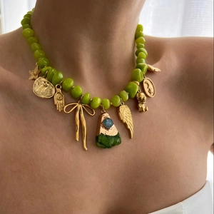 Golden butterfly pendant necklace with green beads and mixed charms on a female model