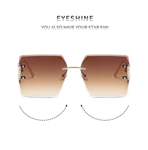 Close-up of rimless square sunglasses with brown gradient lenses and gold floral metal hinges