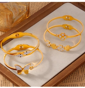 Detail of elegant gold-plated titanium steel bracelets with clover and butterfly motifs