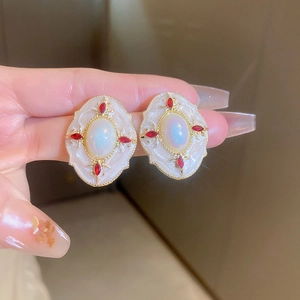 Détail de boucles d'oreilles vintage avec pierres marquises rouges et émail blanc
