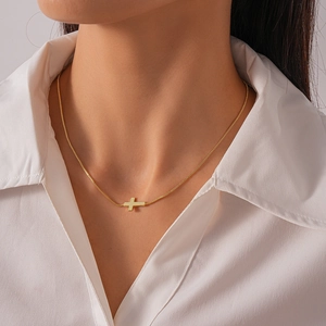 Close-up of a minimalist 18k gold plated horizontal cross pendant necklace on a model