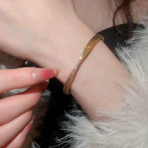 Detail of elegant gold-toned twisted bangle featuring a sparkling pavé-set diamond texture