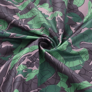 Close-up of soft floral camo fabric texture with green and purple tones and tight knit