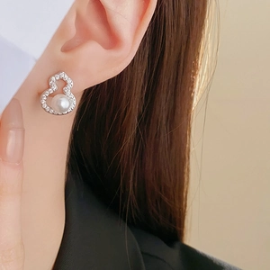 Close-up of elegant silver gourd earring with sparkling zircons and a glossy white pearl