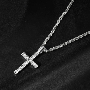 Macro shot of silver hip hop cross pendant with rhinestones on black silk background