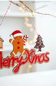Wooden gingerbread man Merry Xmas ornament hanging on a Christmas tree branch