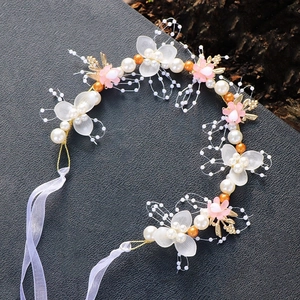 Detail eines handgemachten Blumen-Haarreifs mit weißen Perlen und matten Blütenblättern