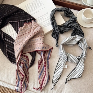 Vintage striped fabric scarf necklace with floral patterns on rustic book background