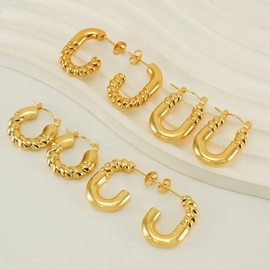 Lot de quatre boucles d'oreilles créoles dorées en acier inoxydable sur support blanc