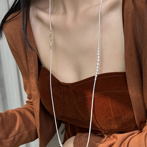 Elegant long pearl necklace with gradient beads and gold clasp on brown velvet dress