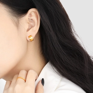 Minimalist gold-plated titanium steel earrings and textured ring worn by a model